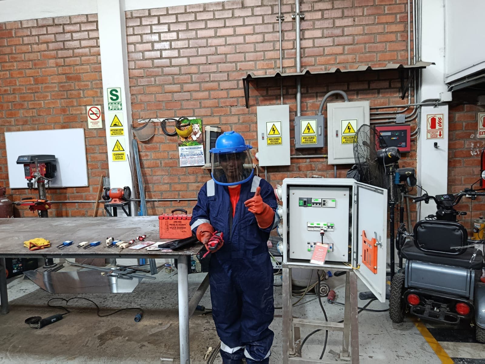 Participante con traje de arco eléctrico frente a un tablero eléctrico abierto